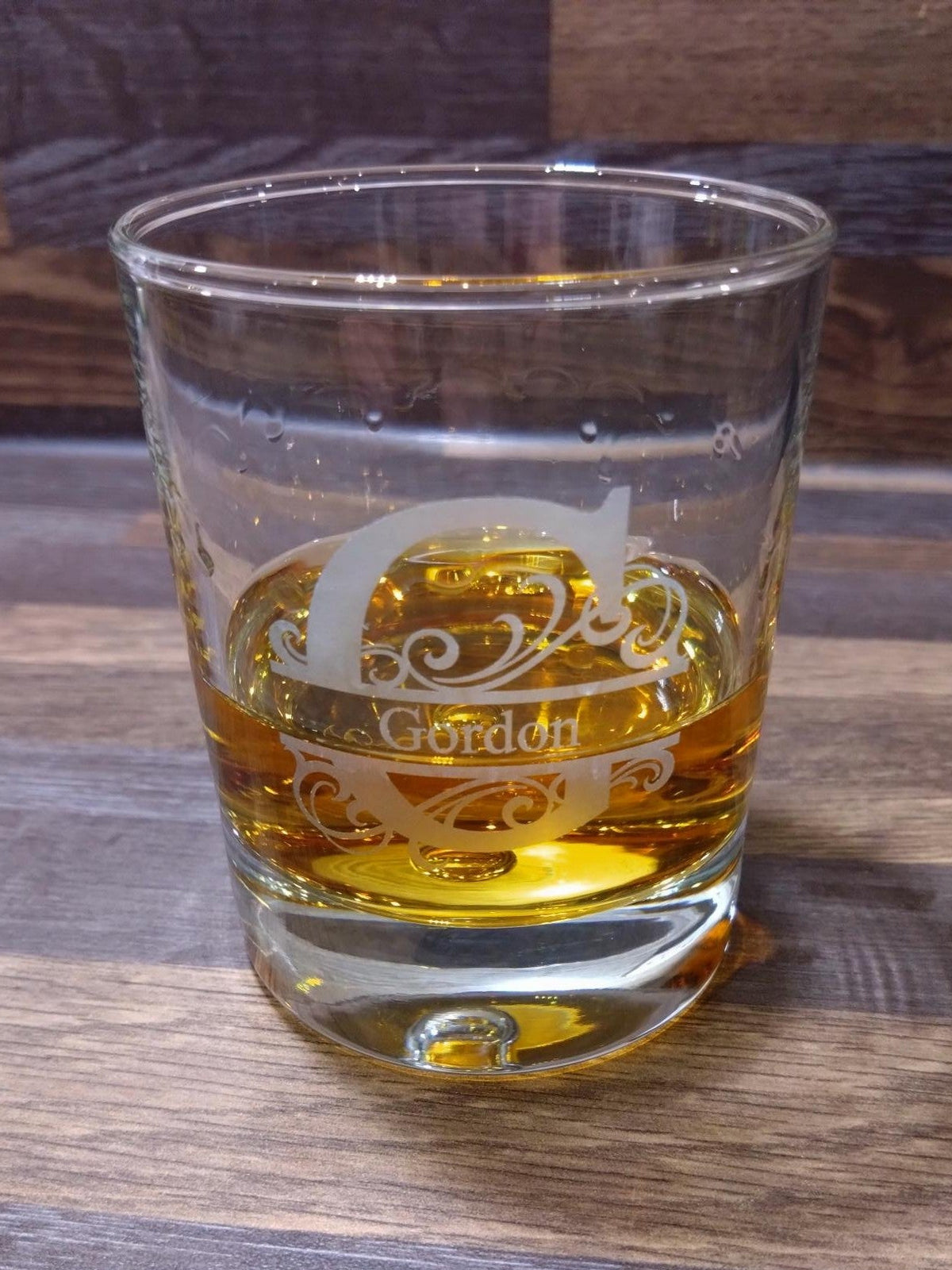 Glass of amber liquid with a decorative emblem on a wooden surface