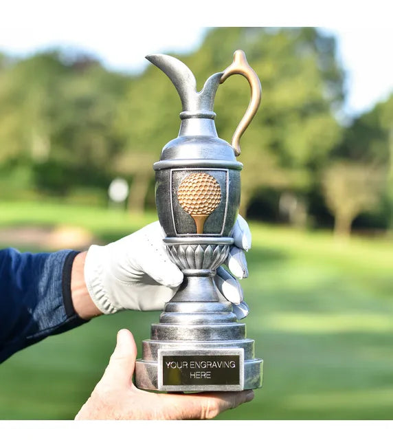 Golf trophy held by a gloved hand with a golf course in the background