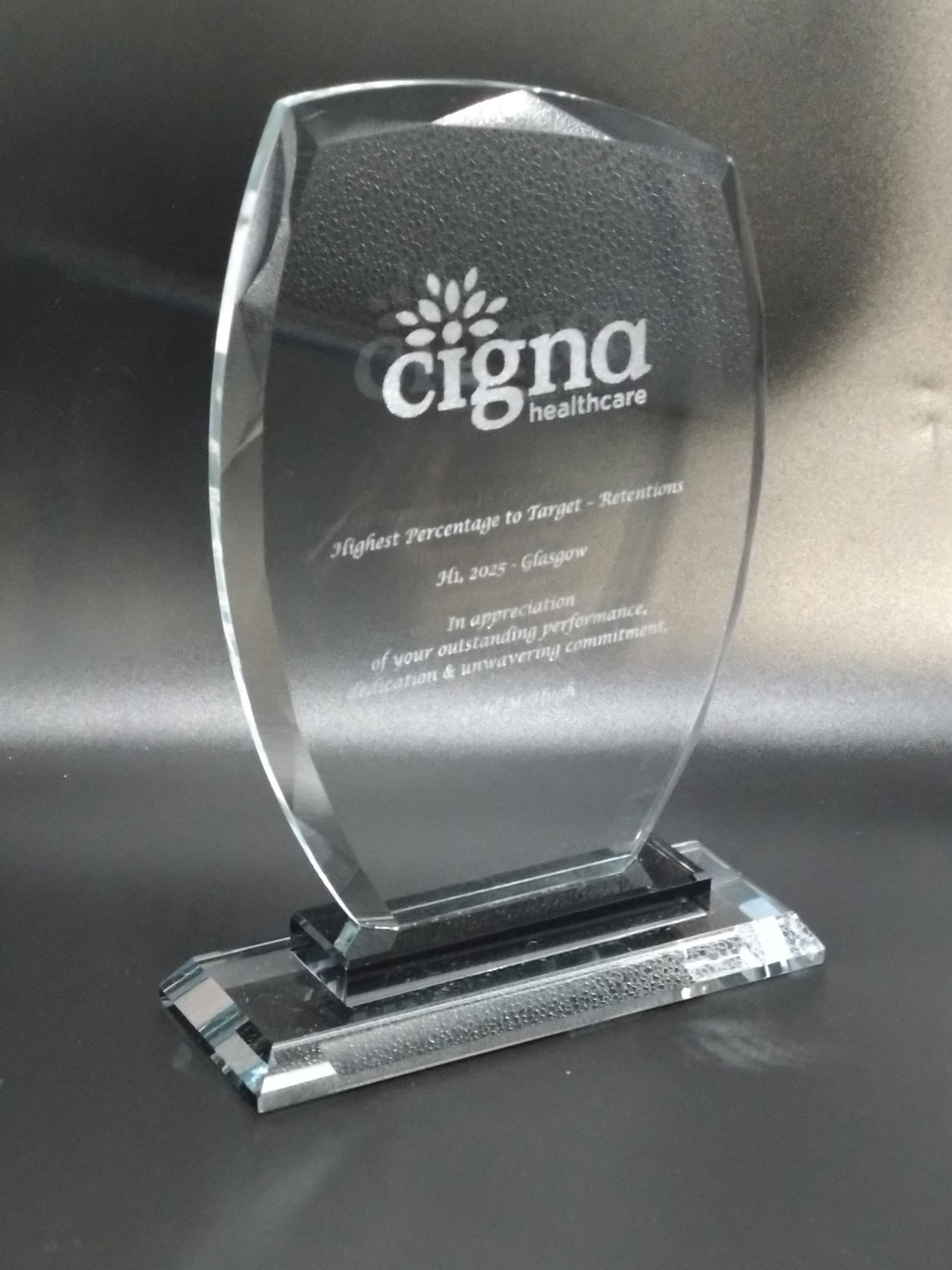 Clear glass award with Cigna Healthcare logo on a reflective surface
