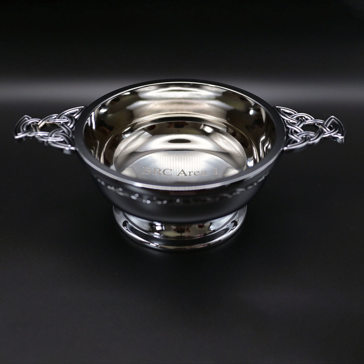 Silver quaich bowl with Celtic design on a black background