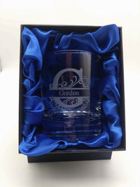 Glass tumbler with engraved design and 'Gordon' text, placed in a blue box with blue satin lining.
