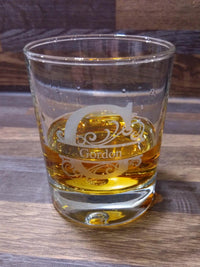 Glass of amber liquid with a decorative emblem on a wooden surface