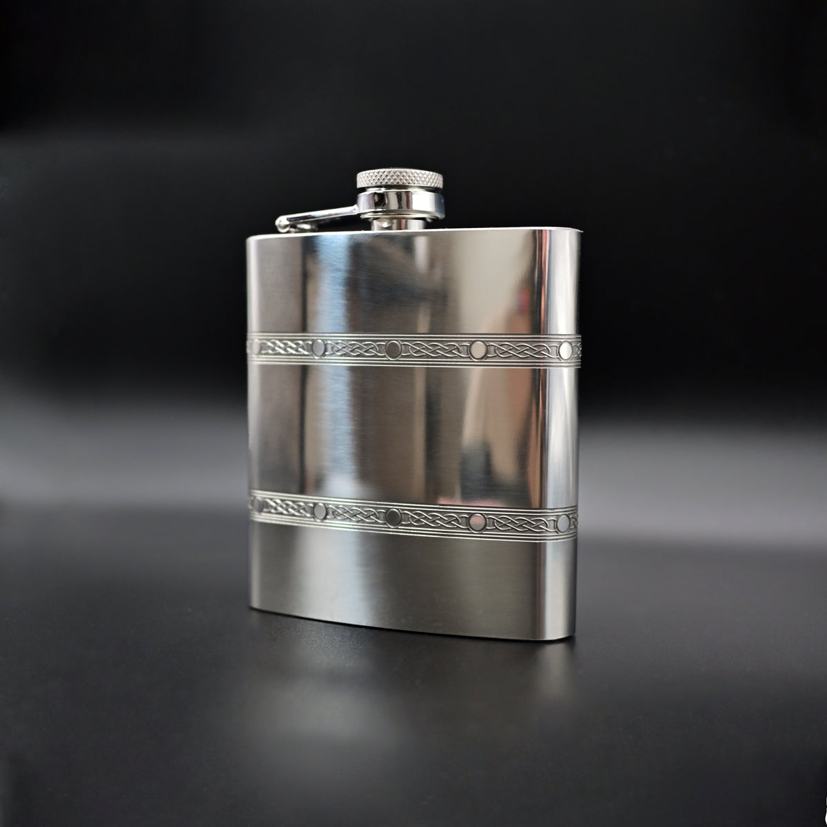 Silver flask with decorative band on a black background