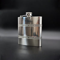 Silver flask with decorative band on a black background