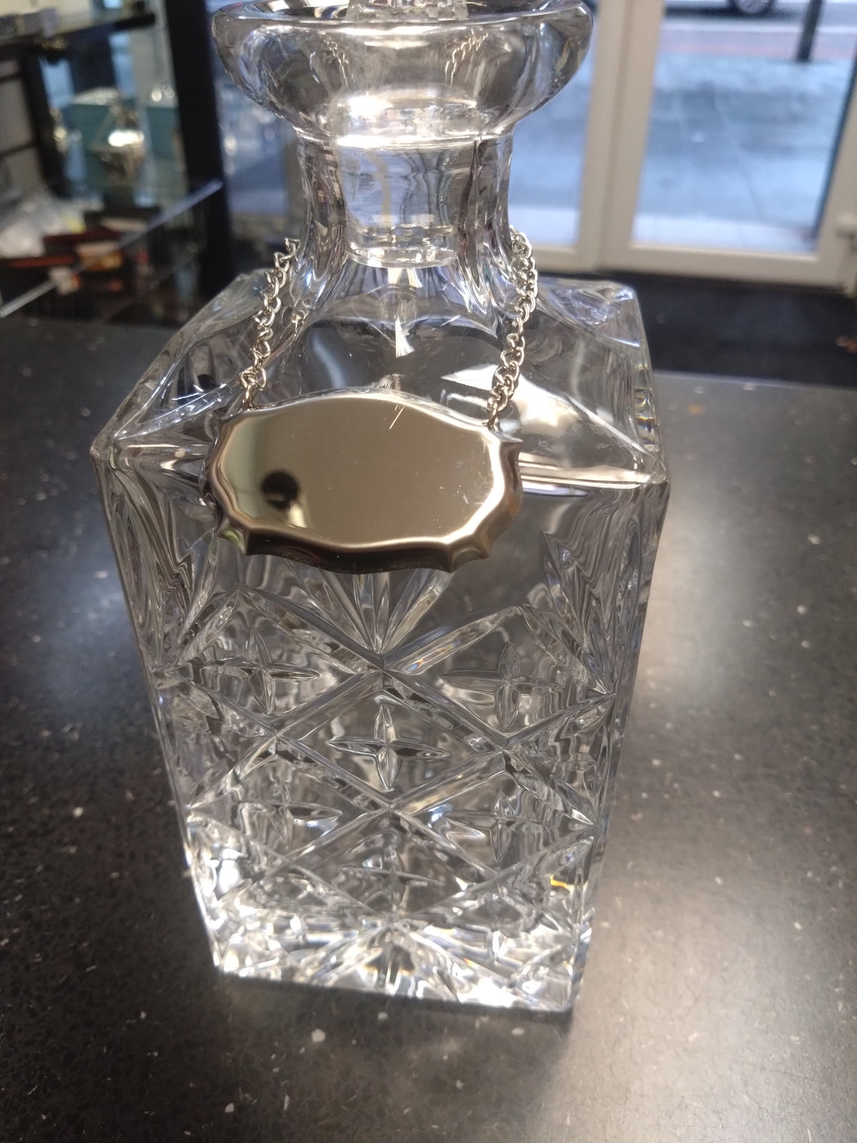 Stainless steel decanter label on crystal decanter on a shop counter