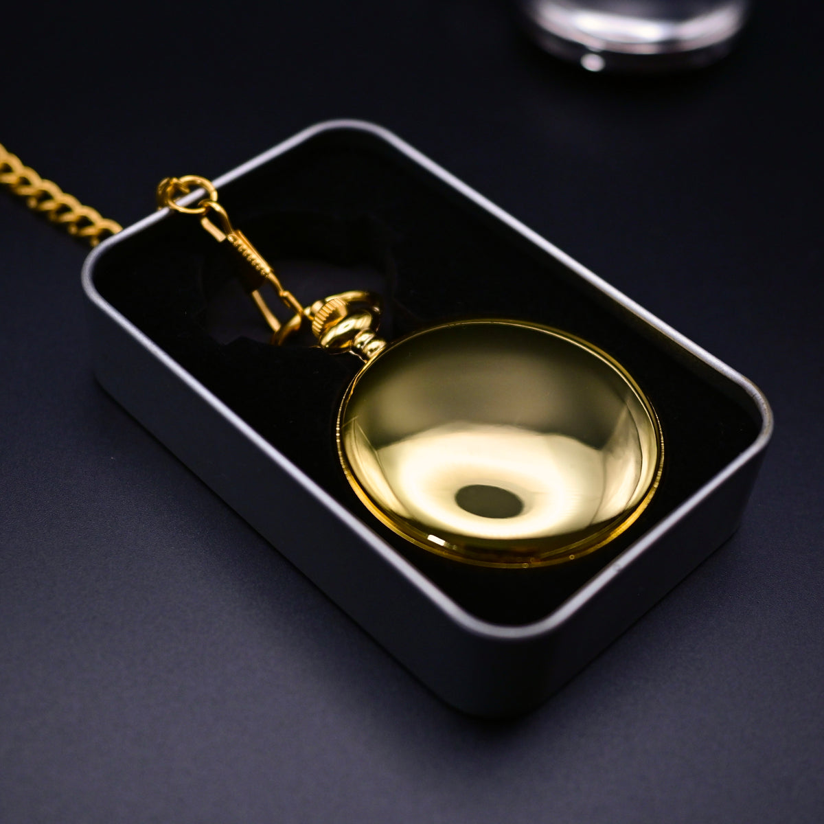 Gold pocket watch in a black box on a dark background
