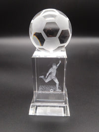 Crystal soccer ball trophy with a player on a dark background