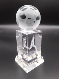 Crystal soccer ball trophy with player figures on a dark background