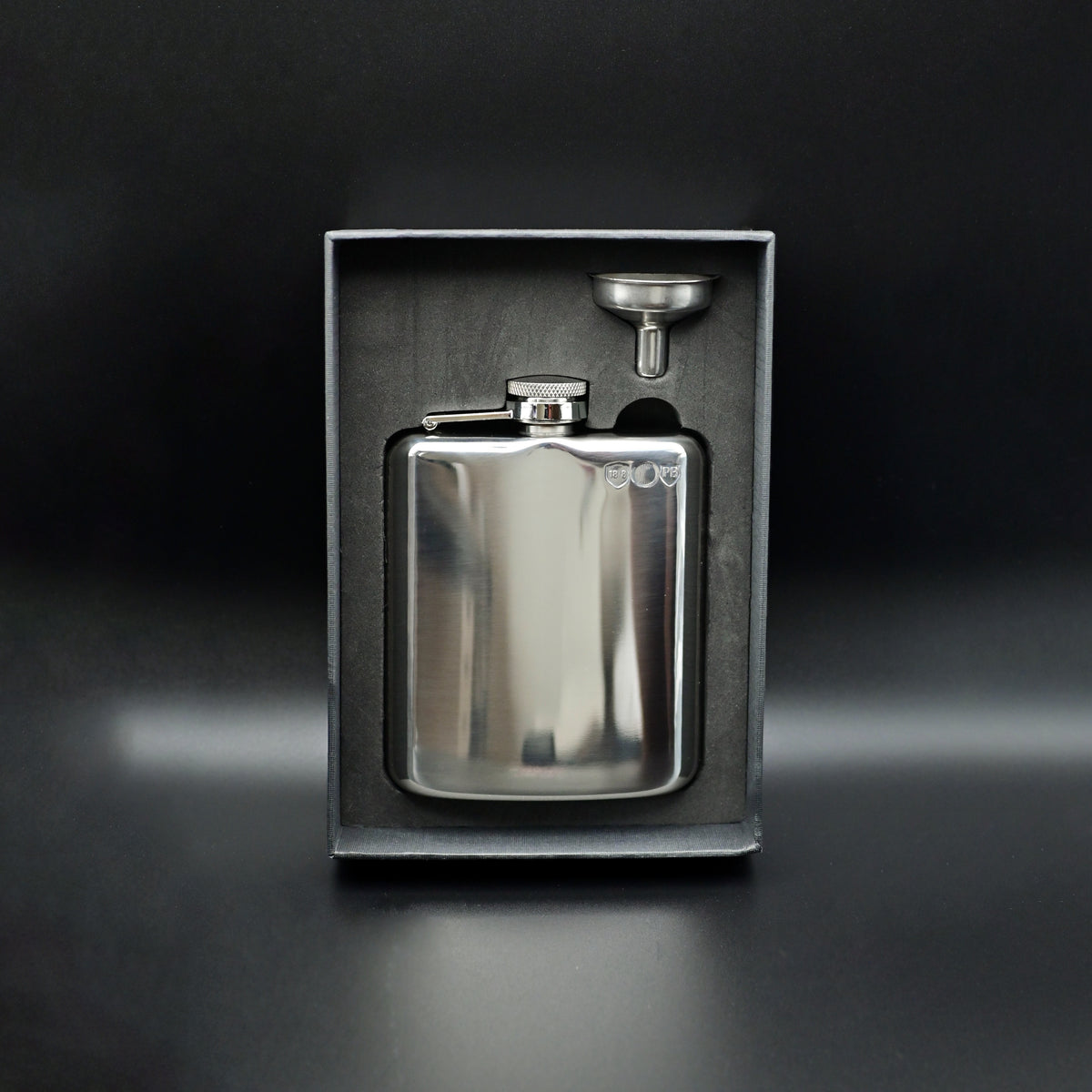 Silver flask with funnel in a black box on a dark background