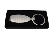 Silver keychain with engraved text on a black display box