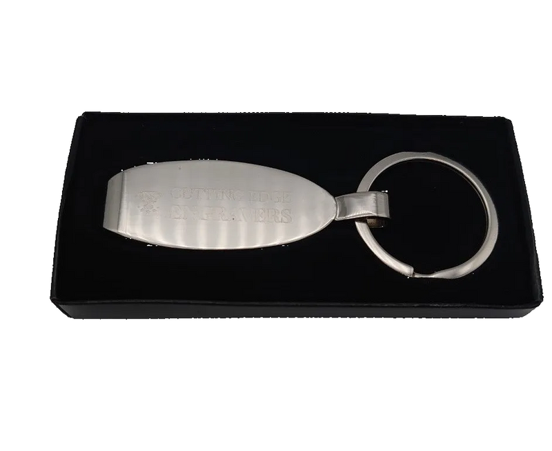 Silver keychain with engraved text on a black display box
