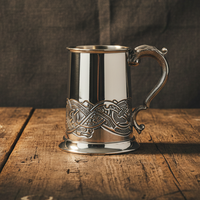 Silver tankard with intricate designs on a wooden surface