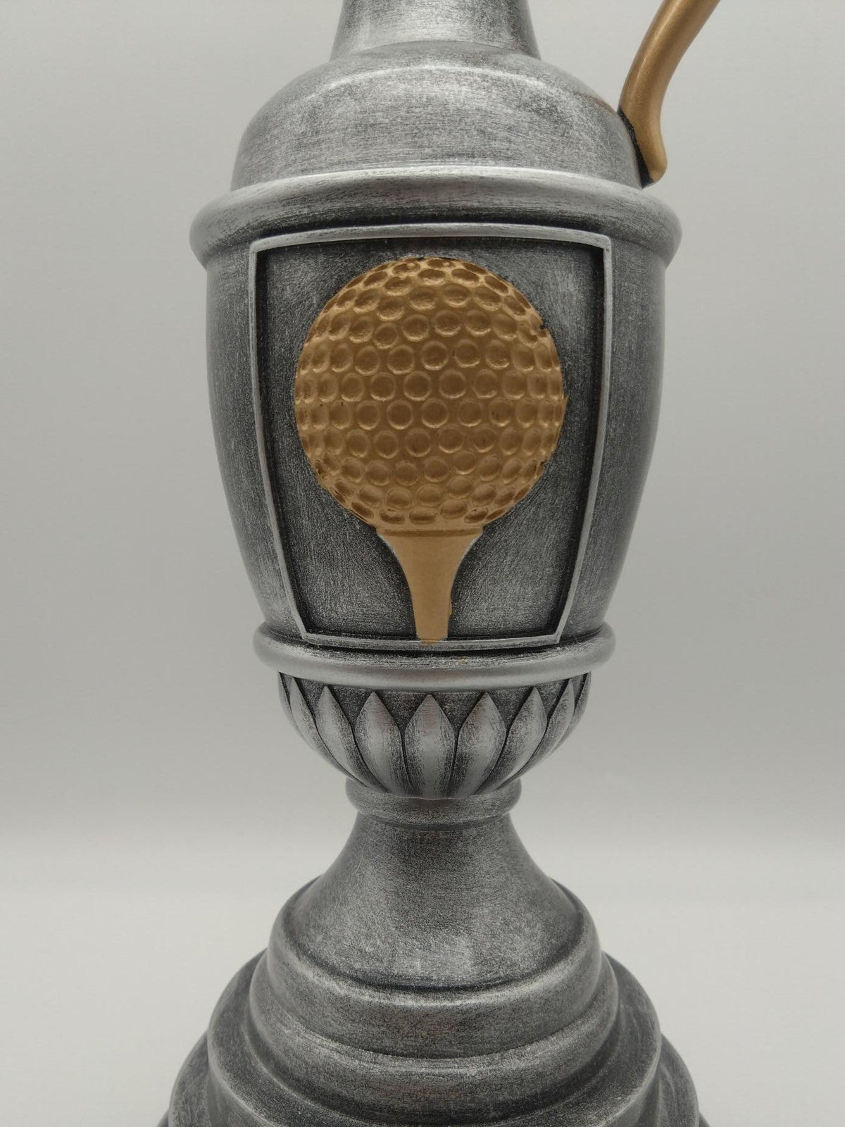 Trophy with a gold golf ball emblem on a gray background