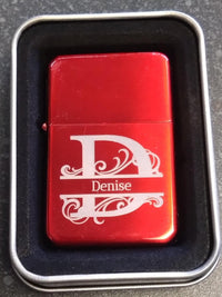 Red lighter with 'Denise' engraving in a metallic case on a dark surface